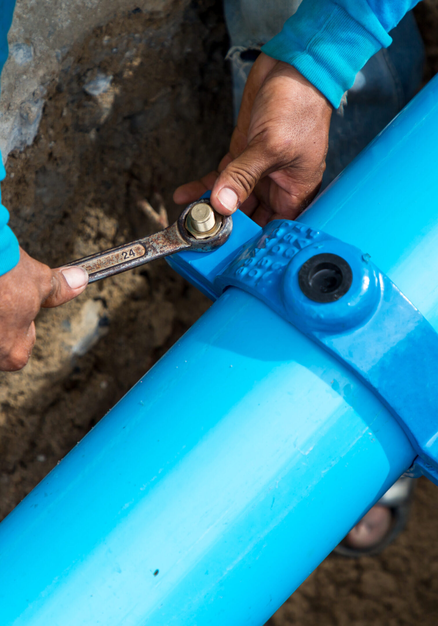 Man using a large wrench on water pipes. Construction site with new Water Pipes in the ground. Sewer pipes to repair or restore in street city.